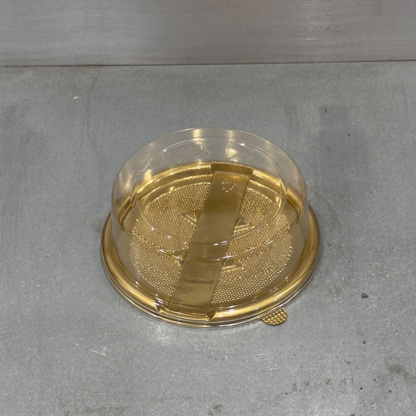 Close up of Marah Design plastic round cake container  with gold tray and closed lid 