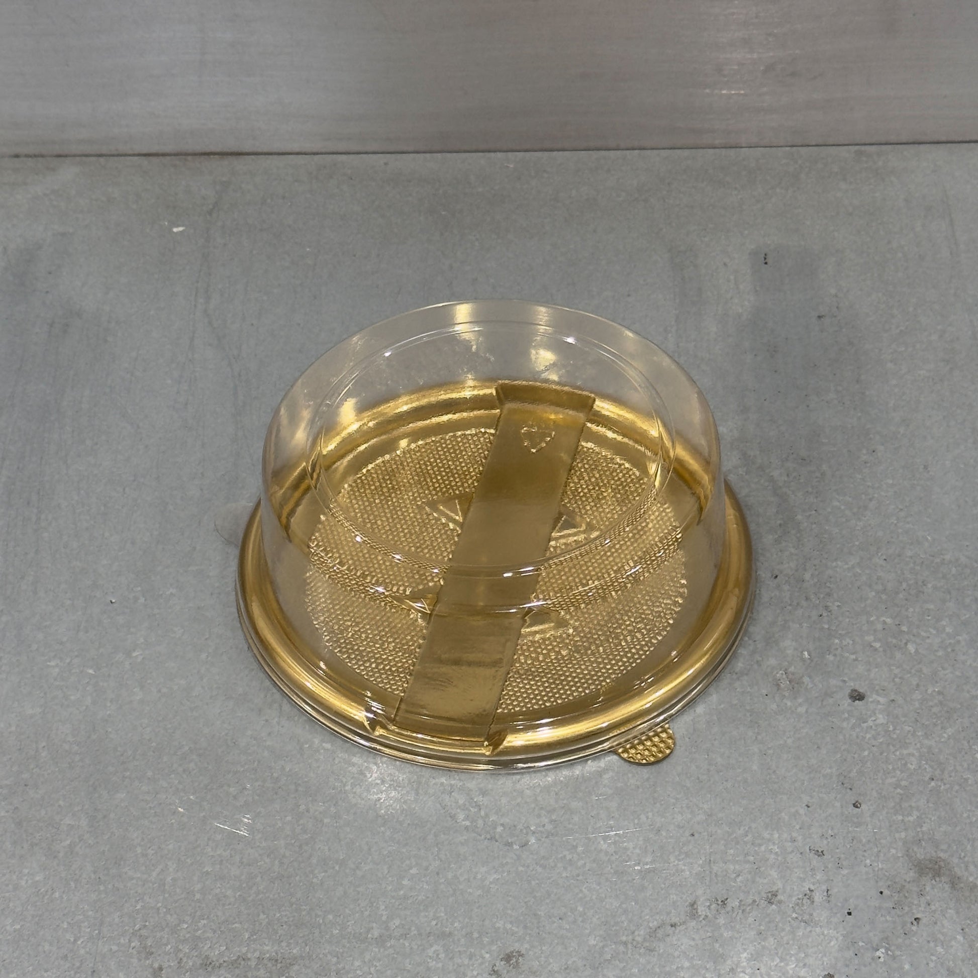 Close up of Marah Design plastic round cake container  with gold tray and closed lid 
