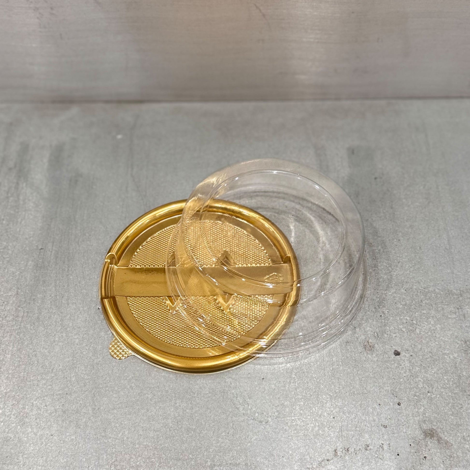 Close up of Marah Design plastic round cake container  with lid and gold tray